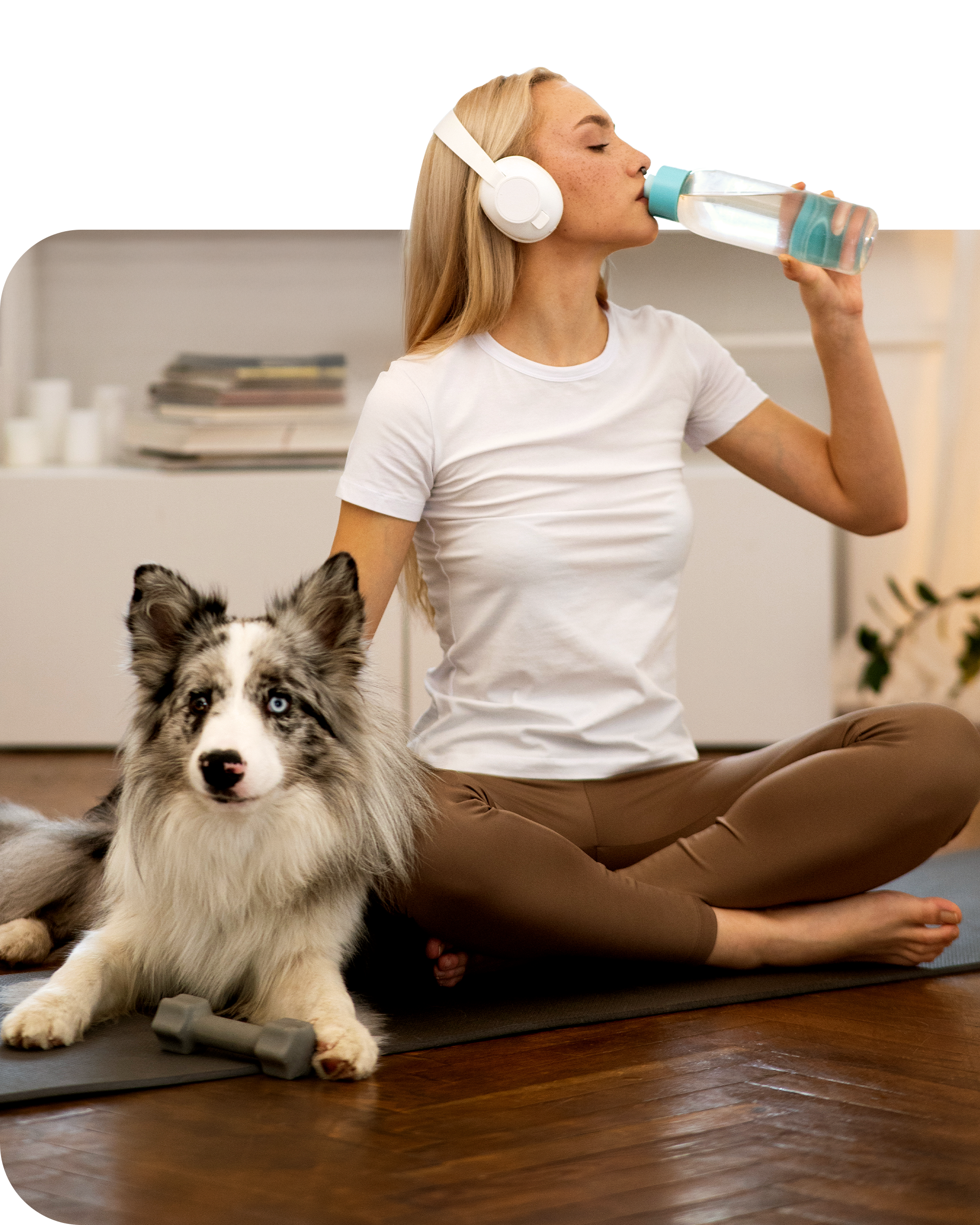 Woman drinking from a water bottle while sitting next to a dog